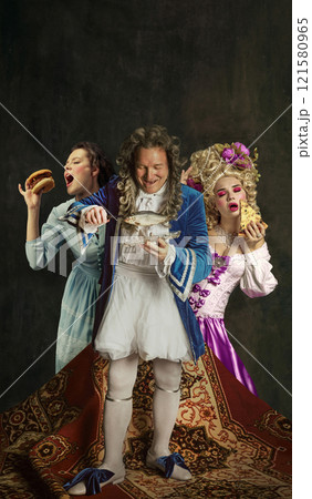 Collage. Playful depiction of three figures in vibrant costumes, noblewoman enjoying pizza, man preparing fish, and another character biting into burger with gusto. 121580965