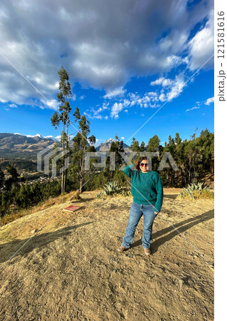 A woman in a green sweater stands in front of a mountain range A woman in a green sweater stands in front of a mountain range 121581616
