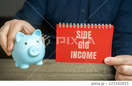 Side gig income refers to earnings generated from work or activities done in addition to a person's primary job. Notebook and piggy bank in male hands. business and finance concept 121582053