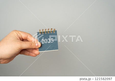 A man holds a notebook 2025 in his hands. Setting goals and objectives for the new year. Planning, business management and strategy concept. Trends and ideas. Vision. 121582097