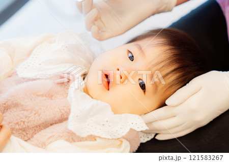 乳児検診を受けて不安顔な乳児 121583267