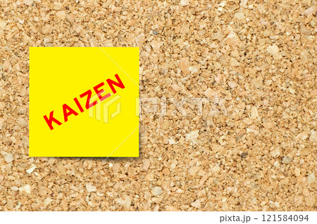 Yellow note paper with word kaizen on cork board background with copy space 121584094