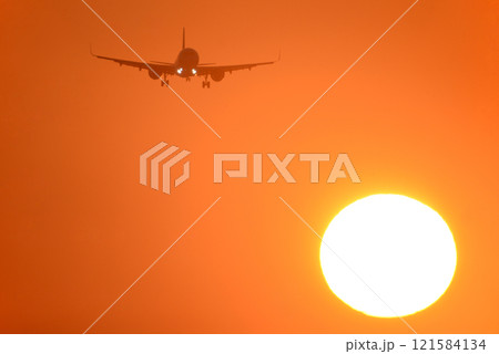 着陸する旅客機と夕陽 121584134
