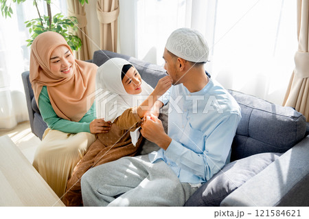 Asian muslim girl touch beard of her young father and stay together with family in living room of their house with day light. 121584621