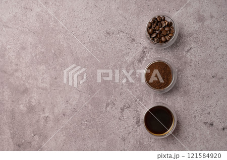 Top view fresh aromatic grain, ground and coffee drink in a small glasses on the side, gray concrete. Copy space background, cover, backdrop, texture. Place for adding text or design 121584920