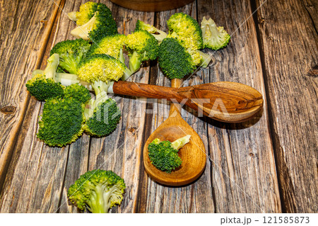 Fresh broccoli pieces with stalks and kitchen spoons on table Fresh broccoli pieces with stalks and kitchen spoons on table 121585873
