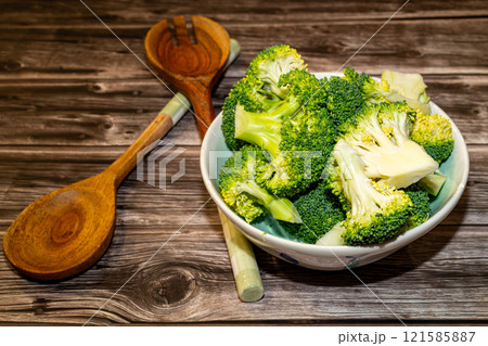 Fresh broccoli pieces with stalks and kitchen spoons on table 121585887