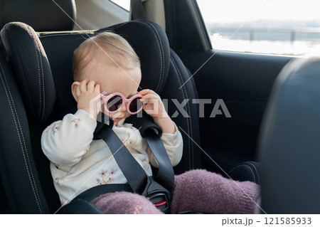 Adorable baby with pink sunglasses in car seat. Concept of safe travel and playful style for little ones Adorable baby with pink sunglasses in car seat. Concept of safe travel and playful style for little ones 121585933