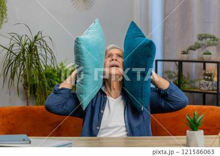 Neighbors repair work irritated man by loud music at home cover ears with pillows annoyed by noise 121586063