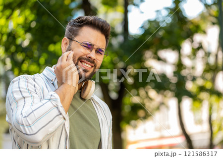 Caucasian young man feeling toothache bad unpleasant symptoms suffering from pain standing on street Caucasian young man feeling toothache bad unpleasant symptoms suffering from pain standing on street 121586317