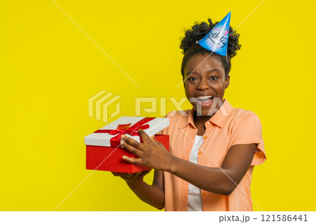 African American woman opening present gift box, party hat, birthday surprise, joyful reaction 121586441
