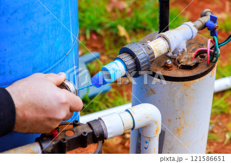 Worker connects PVC pipes water well system, ensuring clean water access in near new home Worker connects PVC pipes water well system, ensuring clean water access in near new home 121586651