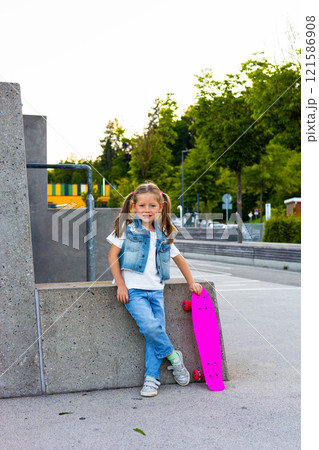 Cute little girl stands with a skateboard 121586908