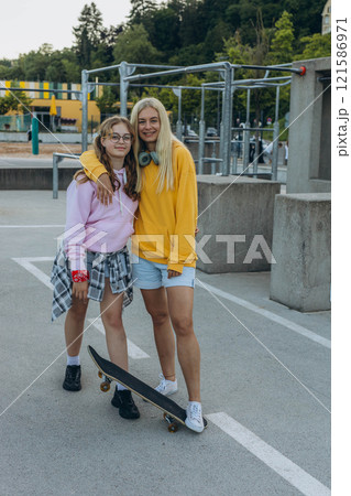young mother with her daughter riding a skateboard in the park. mother with teenager 121586971
