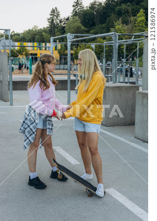 young mother with her daughter riding a skateboard in the park. mother with teenager young mother with her daughter riding a skateboard in the park. mother with teenager 121586974