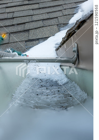 Ice and snow building up inside a rooftop gutter system on a residential house Ice and snow building up inside a rooftop gutter system on a residential house 121590568