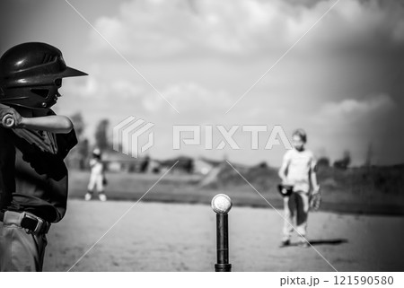 Youth batter hitting a tee ball into an open field at game 121590580
