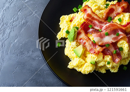 An overhead view showcases a keto breakfast of scrambled eggs, crispy bacon and avocado beautifully 121591661