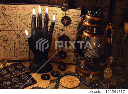 Mystic still life with tarot cards, runes and black candle as scary hand on witch table. Occult, esoteric, wicca, Halloween and gothic concept. No foreign language, all symbols are fictional. 121591717