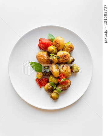 Overhead view of plate with roasted baby potatoes, Brussels sprouts, and cherry tomatoes garnished with fresh basil, clean eating concept with copy space. Overhead view of plate with roasted baby potatoes, Brussels sprouts, and cherry tomatoes garnished with fresh basil, clean eating concept with copy space. 121592737