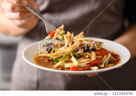 Spicy papaya salad (Som Tum) with hand and eating, Local Thai food 121592856