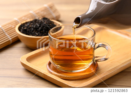 Black tea in cup glass with teapot pouring tea, Healthy herbal drink 121592863