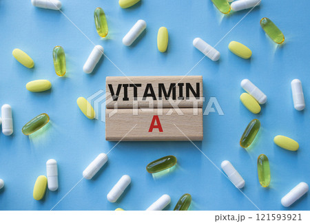 Vitamin A symbol. Concept word Vitamin A on wooden blocks. Beautiful blue background with pills. Medicine and Vitamin A concept. Copy space Vitamin A symbol. Concept word Vitamin A on wooden blocks. Beautiful blue background with pills. Medicine and Vitamin A concept. Copy space 121593921
