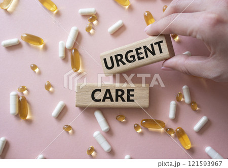 Urgent Care symbol. Concept word Urgent Care on wooden blocks. Beautiful pink background with pills. Doctor Hand. Medicine and Urgent Care concept. Copy space 121593967
