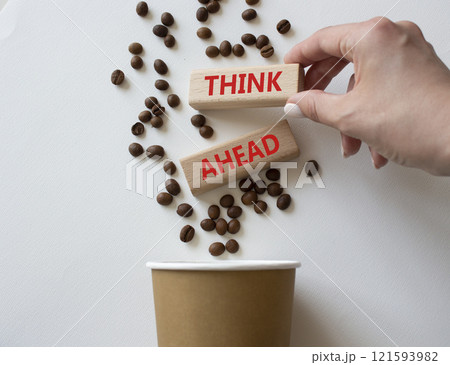 Think ahead symbol. Concept word Think ahead on wooden blocks. Businessman hand. Beautiful white background with coffee cup. Business and Think ahead concept. Copy space Think ahead symbol. Concept word Think ahead on wooden blocks. Businessman hand. Beautiful white background with coffee cup. Business and Think ahead concept. Copy space 121593982