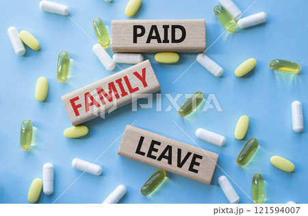 Paid Family Leave symbol. Concept words Paid Family Leave on wooden blocks. Beautiful blue background with pills. Healthcare and Paid Family Leave concept. Copy space. 121594007
