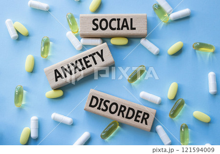 Social Anxiety Disorder symbol. Concept words Social Anxiety Disorder on wooden blocks. Beautiful blue background with pills. Healthcare and Social Anxiety Disorder concept. Copy space. 121594009