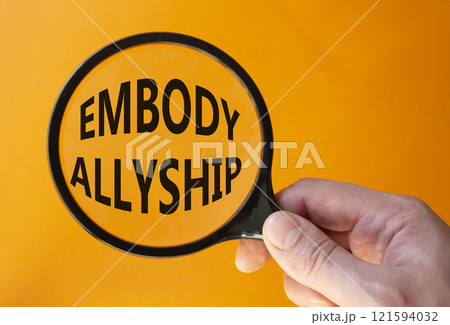 Embody Allyship symbol. Concept word Embody Allyship on magnifying glass. Beautiful orange background. Businessman hand. Business and Embody Allyship concept. Copy space Embody Allyship symbol. Concept word Embody Allyship on magnifying glass. Beautiful orange background. Businessman hand. Business and Embody Allyship concept. Copy space 121594032