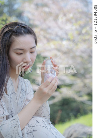 桜の下で桜の花びらの瓶を持つ女性 桜の下で桜の花びらの瓶を持つ女性 121594088