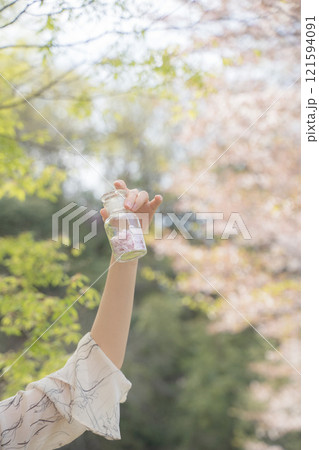桜の下で桜の花びらの瓶を持つ女性 桜の下で桜の花びらの瓶を持つ女性 121594091