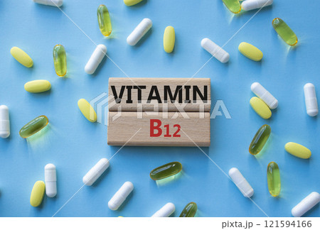 Vitamin B12 symbol. Concept word Vitamin B12 on wooden blocks. Beautiful blue background with pills. Medicine and Vitamin B12 concept. Copy space 121594166