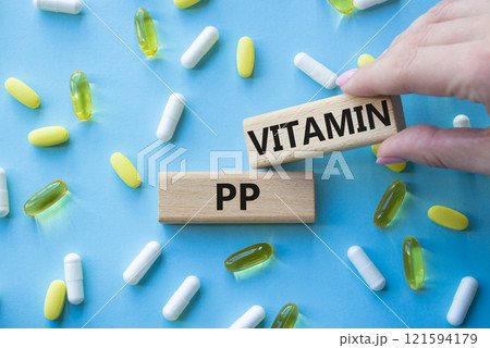 Vitamin PP symbol. Concept word Vitamin PP on wooden blocks. Beautiful pink background with pills. Doctor hand. Medicine and Vitamin PP concept. Copy space Vitamin PP symbol. Concept word Vitamin PP on wooden blocks. Beautiful pink background with pills. Doctor hand. Medicine and Vitamin PP concept. Copy space 121594179