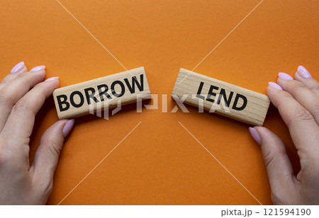 Lend or Borrow symbol. Concept word Lend or Borrow on wooden blocks. Businessman hand. Beautiful orange background. Business and Lend or Borrow concept. Copy space 121594190