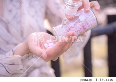 桜の花びらを閉じ込めた瓶を手に持つ女性の手元 桜の花びらを閉じ込めた瓶を手に持つ女性の手元 121594330