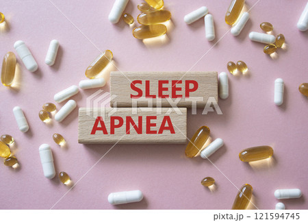 Sleep Apnea symbol. Concept word Sleep Apnea on wooden blocks. Beautiful pink background with pills. Medicine and Sleep Apnea concept. Copy space 121594745