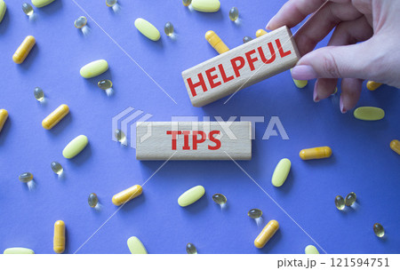 Helpful tips symbol. Concept word Helpful tips on wooden blocks. Doctor Hand. Beautiful purple background with pills. Medicine and Helpful tips concept. Copy space 121594751