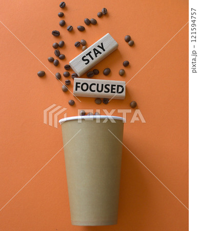 Stay Focused symbol. Concept word Stay Focused on wooden blocks. Beautiful orange background with coffee cup. Business and Stay Focused concept. Copy space 121594757