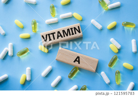 Vitamin A symbol. Concept word Vitamin A on wooden blocks. Beautiful blue background with pills. Medicine and Vitamin A concept. Copy space Vitamin A symbol. Concept word Vitamin A on wooden blocks. Beautiful blue background with pills. Medicine and Vitamin A concept. Copy space 121595783