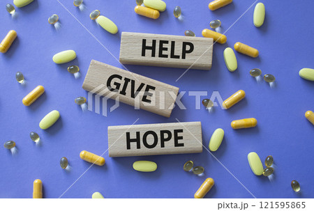 Help Give Hope symbol. Concept word Help Give Hope on wooden blocks. Beautiful purple background with pills. Medicine and Help Give Hope concept. Copy space 121595865