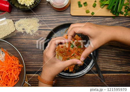 Hands making heart shape over plate of freshly homemade Kimchi on rustic wooden table 121595970