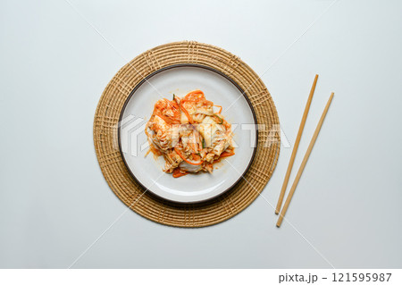 Traditional Korean Kimchi on a rustic Plate accompanied by wooden chopsticks. Korean cuisine and traditional side dish concept Traditional Korean Kimchi on a rustic Plate accompanied by wooden chopsticks. Korean cuisine and traditional side dish concept 121595987