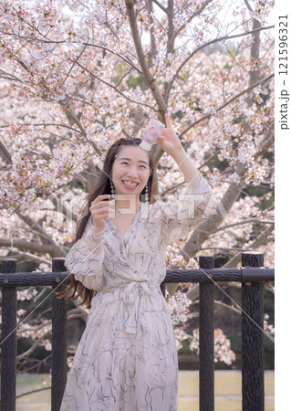 桜の木の下でポーズをとる若い女性 桜の木の下でポーズをとる若い女性 121596321