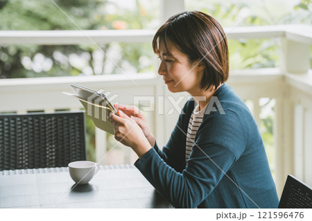 テラスでタブレット端末を使う女性 テラスでタブレット端末を使う女性 121596476