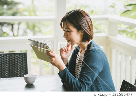 テラスでタブレット端末を使う女性 テラスでタブレット端末を使う女性 121596477