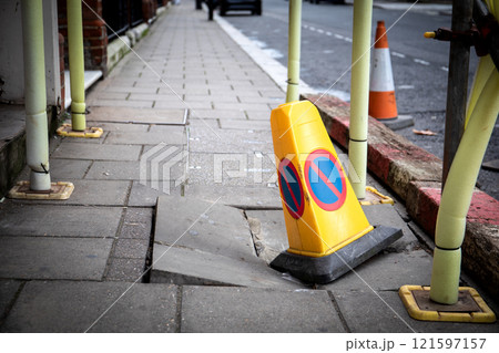 Warning cone on damaged pedestrian sidewalk. Construction site and emergency situation 121597157