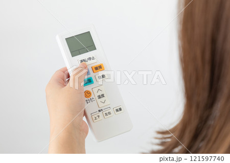 エアコンのリモコンを操作する女性01 121597740